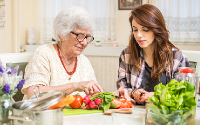 Grandmother and granddaughter preparing food together at kitchen
