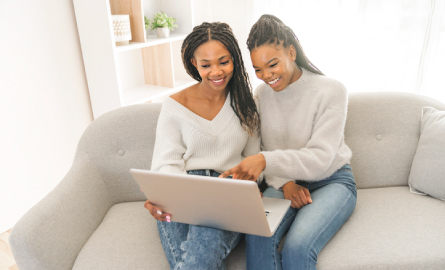 Mother and daughter looking at laptop and smiling